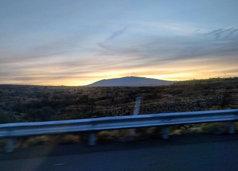 Sunrise over a road and a mountain.
