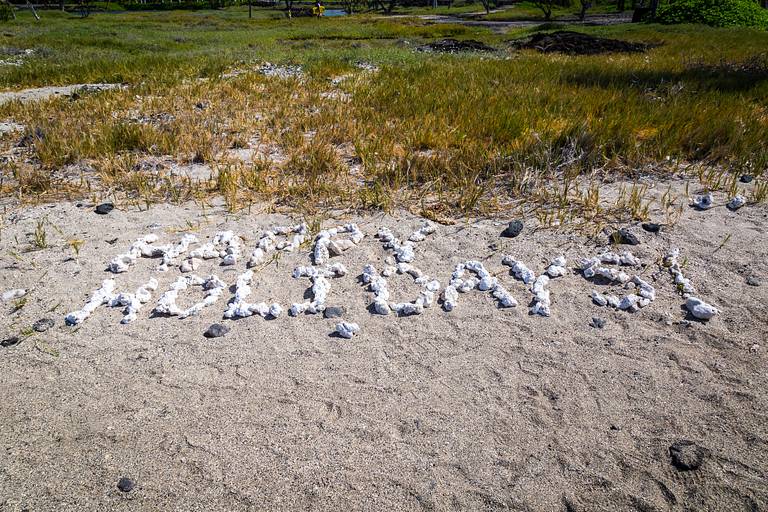Happy holidays written with stones on the beach.